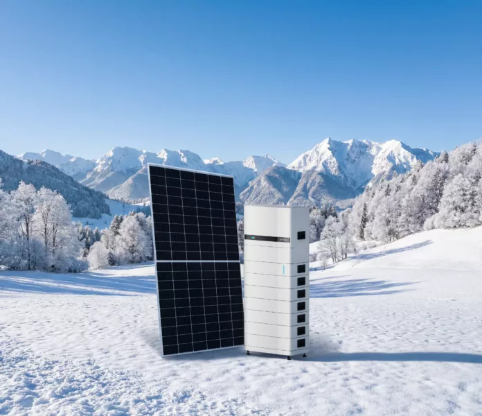 Haus der Energie Photovoltaik Premium im Winter Haus der Energie Photovoltaikmodul mit leistungsstarkem Batteriespeicher in verschneiter Winterlandschaft vor Bergkulisse.
