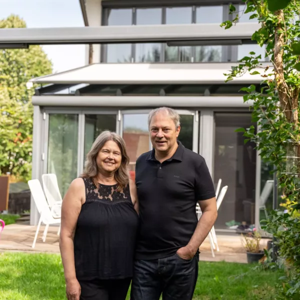 Ehepaar vor ihrem Haus mit Photovoltaik von Haus der Energie
